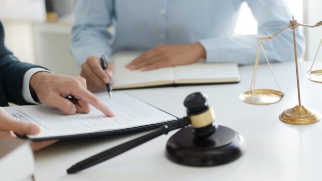 two people sitting at a table with a gavel on it reviewing paperwork