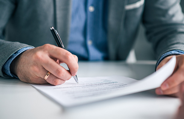 Businessman hand signing contract close up