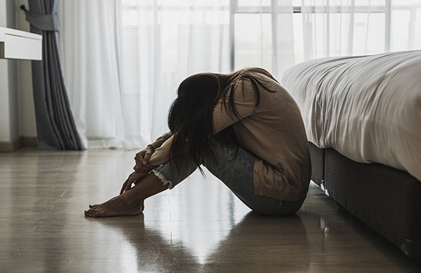 A young woman hugging knees on floor crying from trauma caused by sex crime