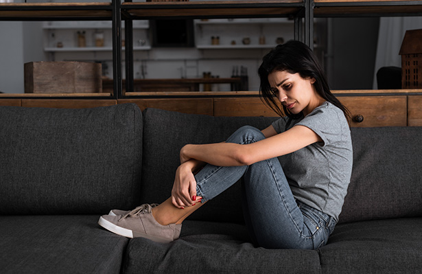 frustrated woman with bruise on face sitting on sofa in living room domestic violence concept