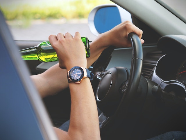 driver of car drinking bottle of beer