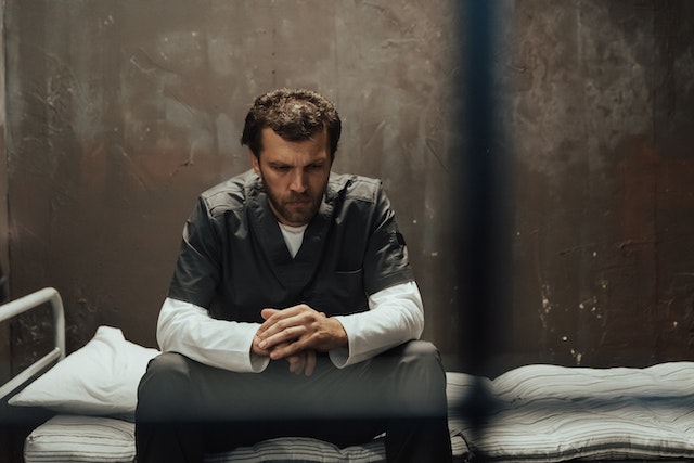 man sitting in prison cell