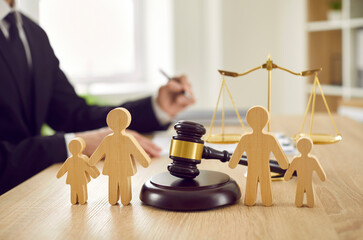 judge with gavel on desk and wooden figurine family