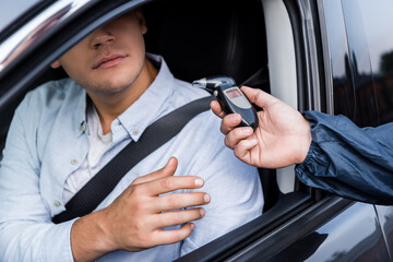 man with breathalyzer in car