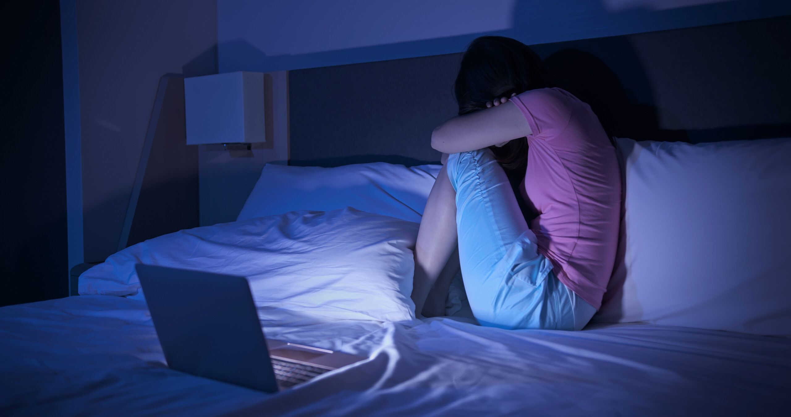 girl with computer in bed cyberbullying harassment