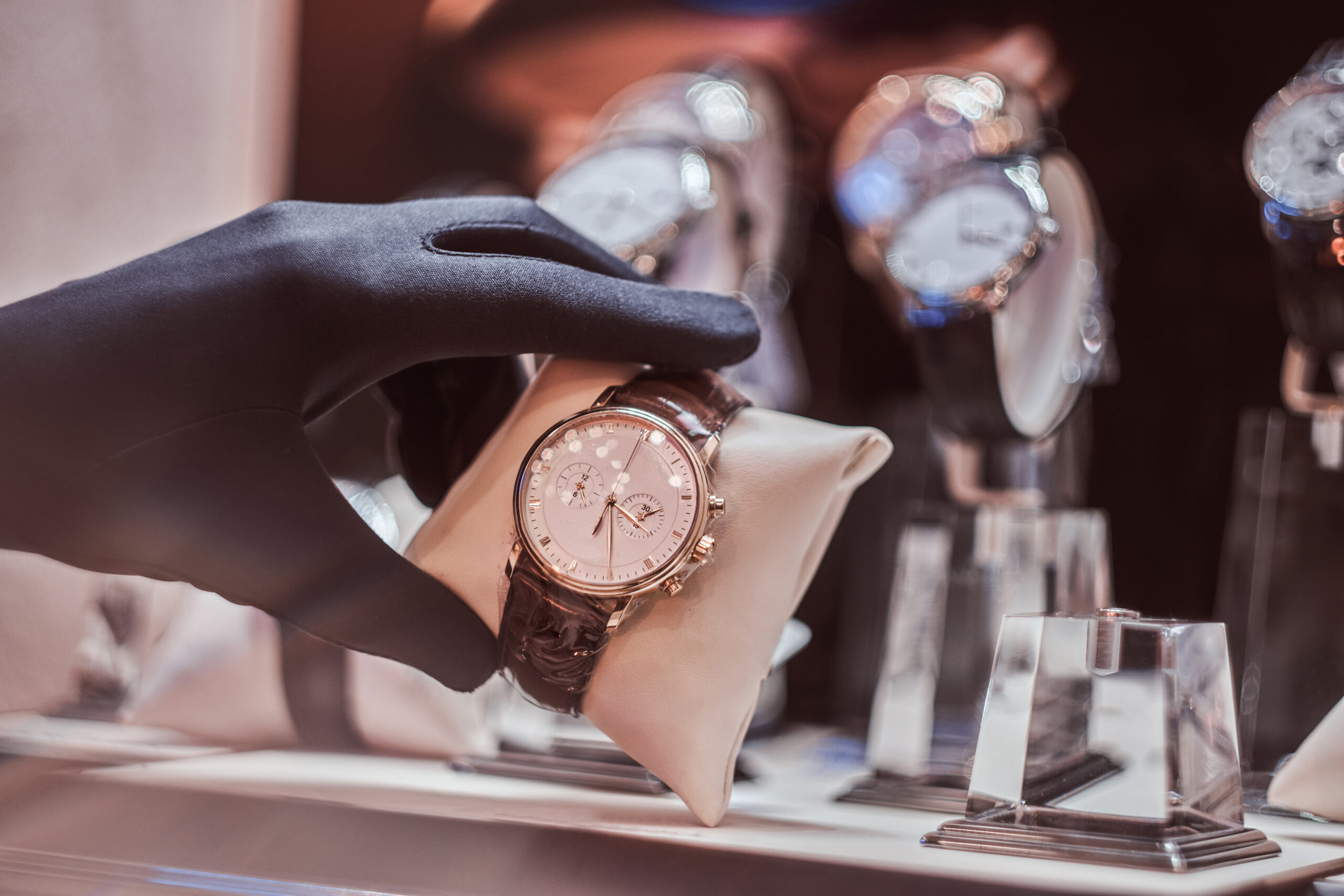 Close-up of the seller's hand in gloves shows the exclusive men's watch from the new collection in the luxury jewelry store